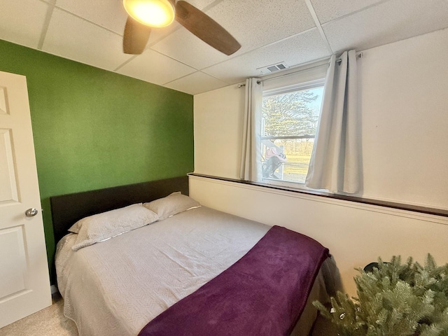 bedroom with visible vents, carpet, ceiling fan, and a drop ceiling