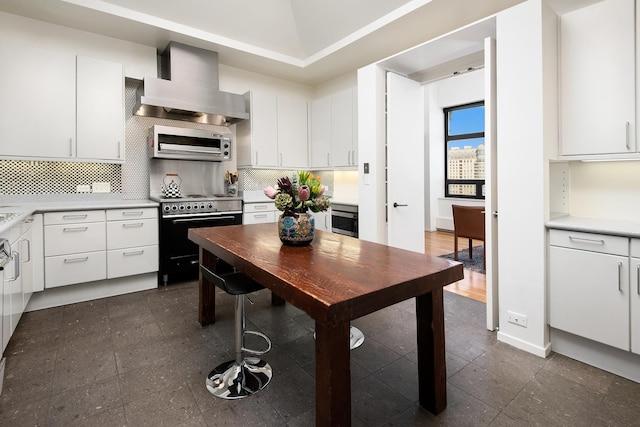 680 N Lake Shore Dr Unit 1602, Chicago, IL 60611 - kitchen with black range with electric cooktop, wall chimney range hood, decorative backsplash, white cabinets, and light countertops