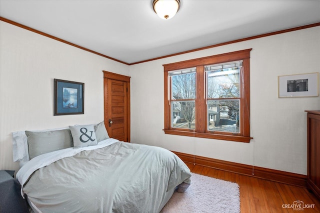 bedroom with baseboards, hardwood / wood-style floors, and ornamental molding