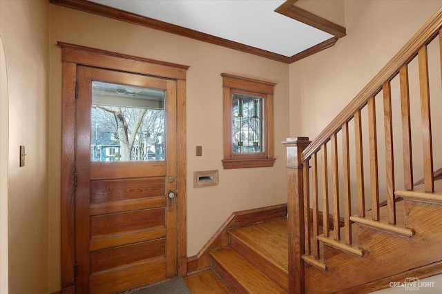 entrance foyer with stairway, wood finished floors, baseboards, and ornamental molding