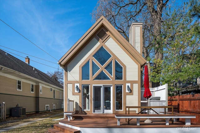 rear view of house with a deck, central AC unit, fence, and a chimney