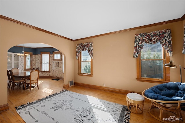 living area with visible vents, arched walkways, light wood finished floors, and baseboards