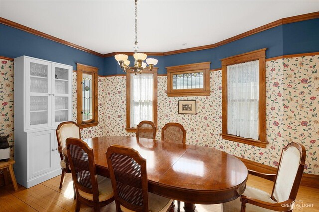 dining space featuring light wood finished floors, wallpapered walls, crown molding, and an inviting chandelier