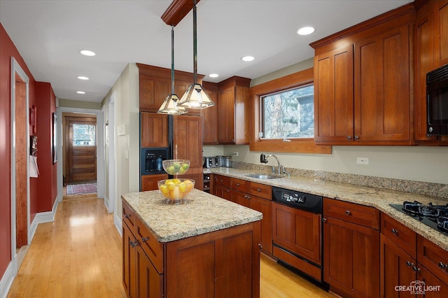 kitchen with a kitchen island, light wood-style flooring, a sink, hanging light fixtures, and black appliances