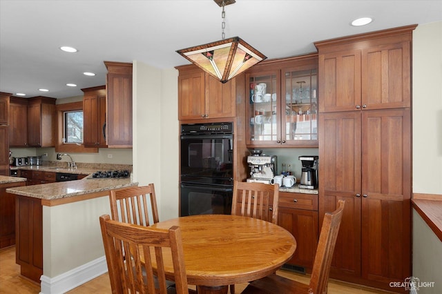 kitchen with glass insert cabinets, a peninsula, gas stovetop, dobule oven black, and a sink