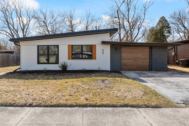 view of front of home with fence, a front yard, cooling unit, a garage, and driveway