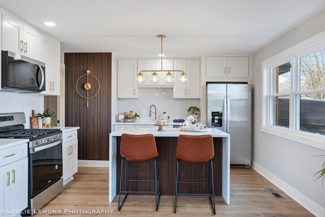 kitchen featuring stainless steel appliances, tasteful backsplash, light countertops, and white cabinetry