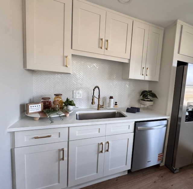 kitchen featuring a sink, stainless steel appliances, backsplash, and light countertops