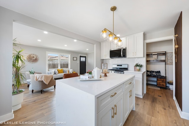 kitchen featuring white cabinets, light wood-style floors, backsplash, and stainless steel appliances