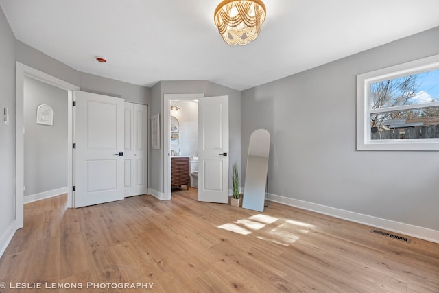 unfurnished bedroom featuring light wood-style floors, arched walkways, and visible vents