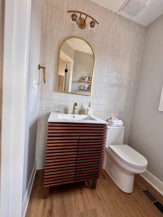 bathroom featuring visible vents, toilet, wood finished floors, and vanity