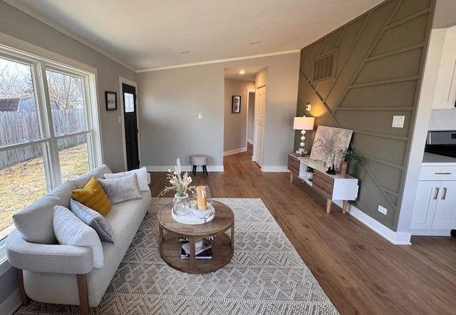 living room with wood finished floors, baseboards, and ornamental molding