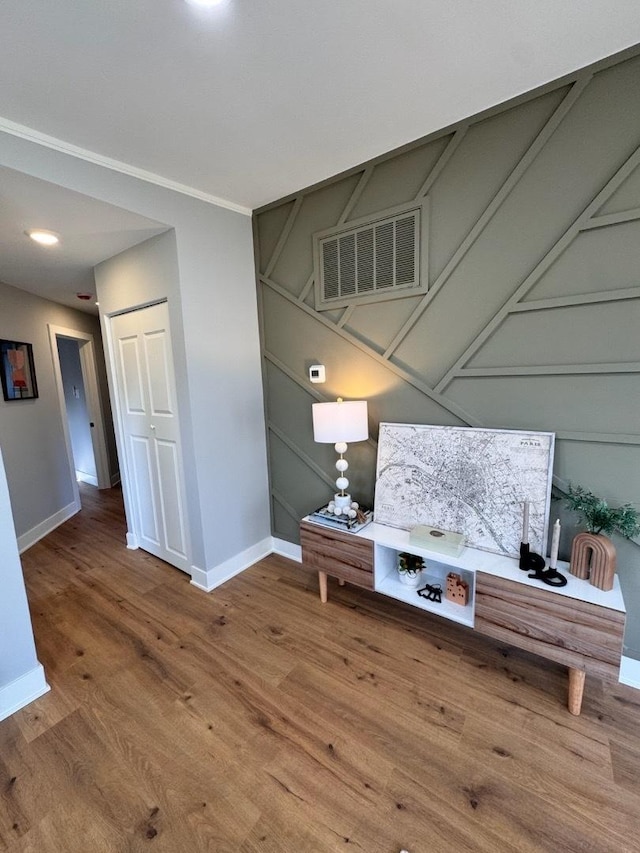 interior space with visible vents, baseboards, wood finished floors, and a decorative wall