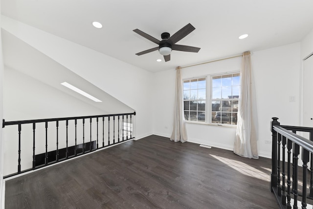 unfurnished room with a skylight, baseboards, wood finished floors, and recessed lighting