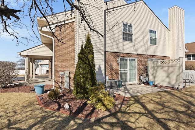 rear view of house featuring fence, a yard, a patio area, and brick siding