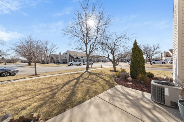 view of yard featuring a residential view and central AC unit