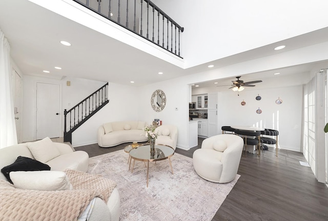 living area featuring baseboards, recessed lighting, stairs, dark wood-type flooring, and a towering ceiling