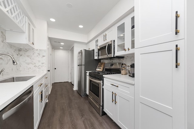 kitchen with appliances with stainless steel finishes, white cabinetry, glass insert cabinets, and a sink