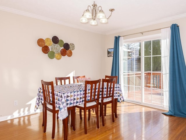 dining space with wood finished floors, baseboards, a chandelier, and ornamental molding