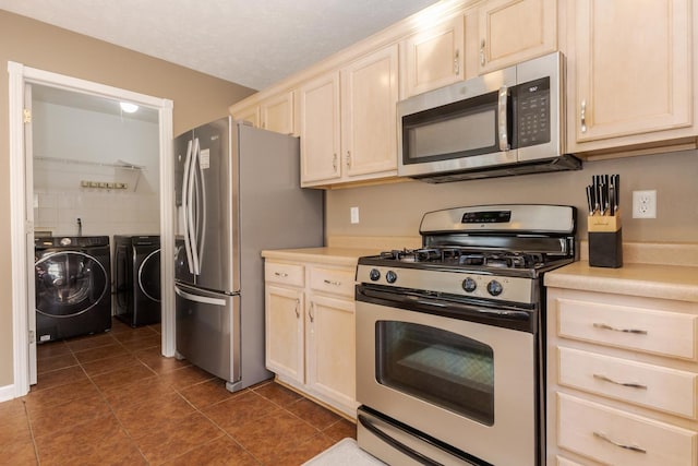 kitchen with dark tile patterned floors, independent washer and dryer, appliances with stainless steel finishes, and light countertops