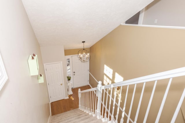 stairway with a notable chandelier, a textured ceiling, and baseboards