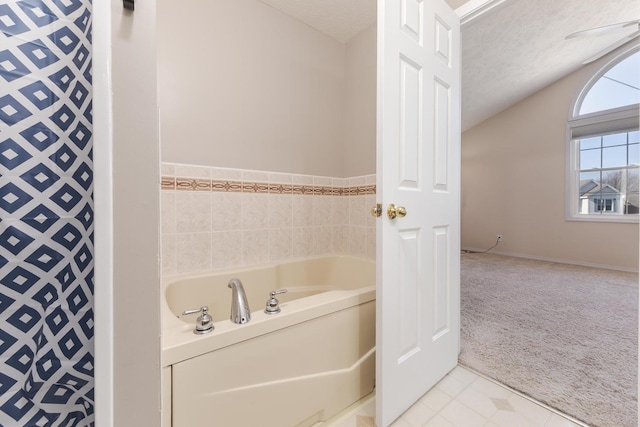 bathroom with tile patterned flooring, vaulted ceiling, a bath, and a textured ceiling