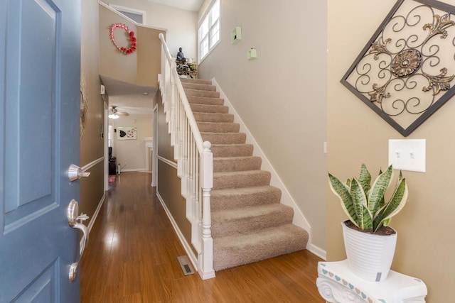 foyer entrance with visible vents, baseboards, stairway, a high ceiling, and wood finished floors