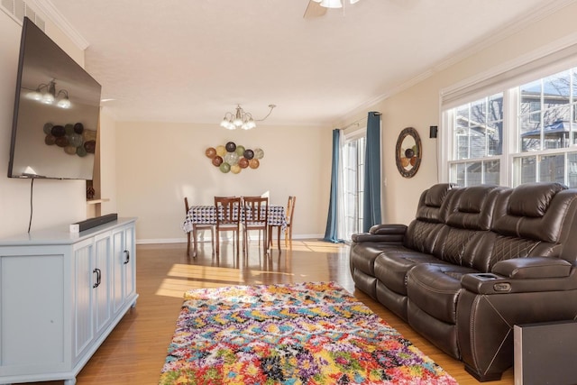 living room with an inviting chandelier, crown molding, light wood-type flooring, and baseboards