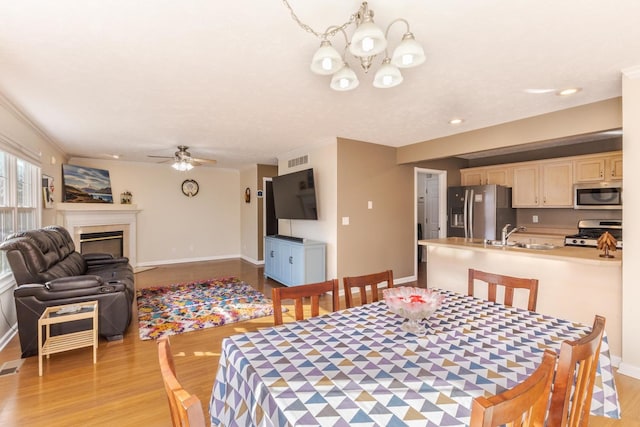 dining room with visible vents, a fireplace, light wood-type flooring, and baseboards