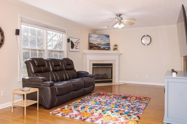 living room featuring a fireplace with flush hearth, wood finished floors, baseboards, and ornamental molding