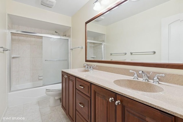 full bath featuring double vanity, toilet, shower / bath combination with glass door, and a sink