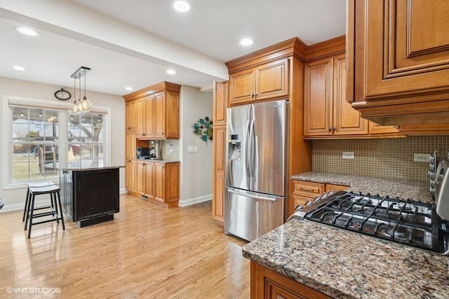 kitchen with light stone counters, stainless steel fridge with ice dispenser, brown cabinets, and light wood finished floors