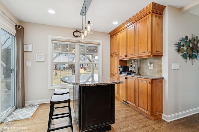 kitchen featuring light stone counters, backsplash, and light wood-style flooring