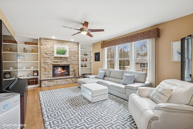 living area featuring a fireplace, light wood-style floors, and ceiling fan