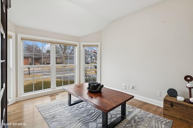 office featuring visible vents, baseboards, light wood-style floors, and vaulted ceiling