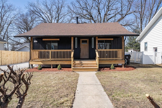 bungalow-style house featuring a front lawn, fence, covered porch, and a shingled roof