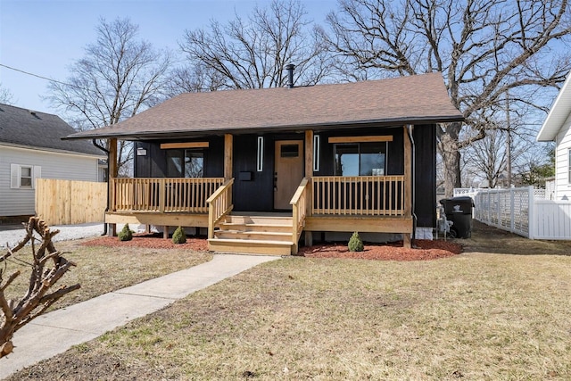 bungalow-style home with covered porch, a shingled roof, and fence