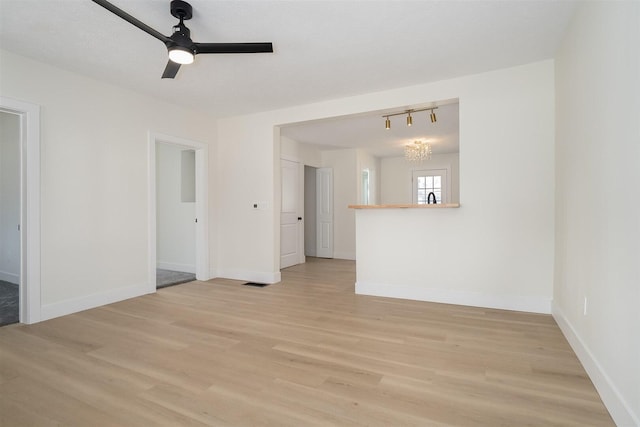 empty room with baseboards, light wood finished floors, visible vents, and ceiling fan with notable chandelier