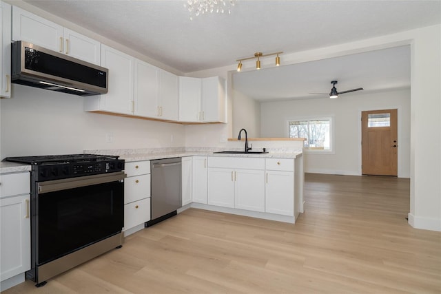 kitchen featuring a peninsula, white cabinets, stainless steel appliances, a ceiling fan, and a sink