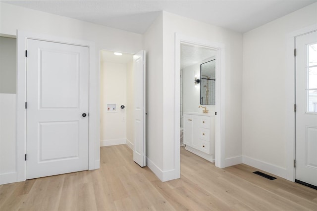 unfurnished bedroom featuring connected bathroom, visible vents, baseboards, and light wood-style flooring