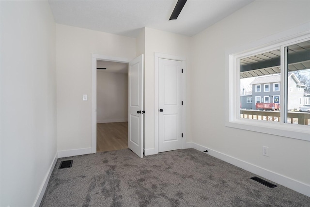 unfurnished bedroom featuring visible vents, carpet floors, baseboards, and a ceiling fan