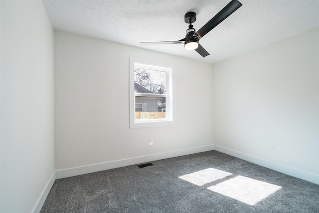 spare room with visible vents, a textured ceiling, dark colored carpet, baseboards, and ceiling fan