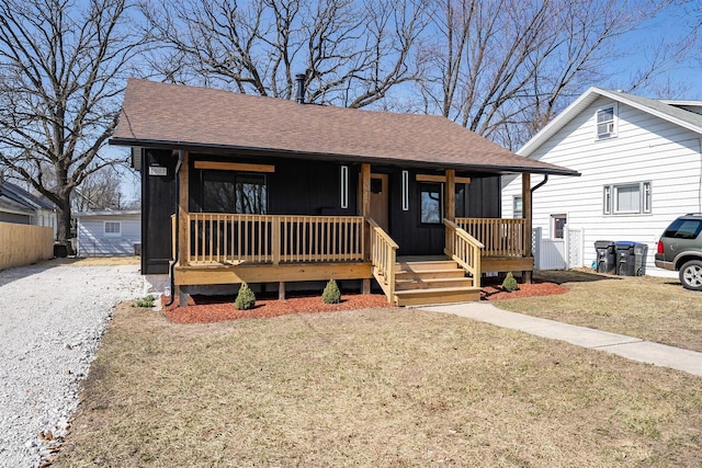 view of front facade featuring a front lawn, covered porch, and roof with shingles