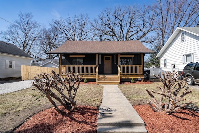 bungalow with roof with shingles, covered porch, and fence