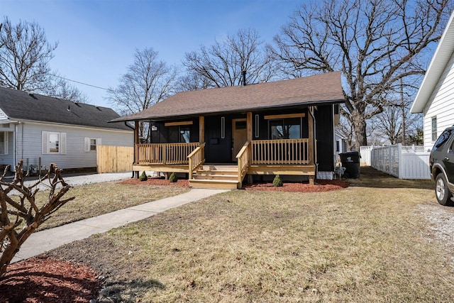 bungalow-style house with a front lawn, fence, covered porch, and roof with shingles