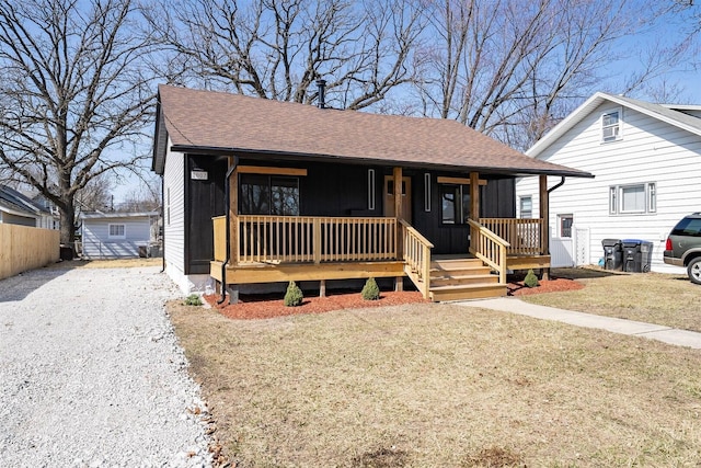 bungalow with a porch, a front lawn, roof with shingles, and fence