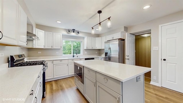 kitchen featuring appliances with stainless steel finishes, a sink, range hood, light countertops, and white cabinets