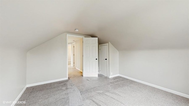 additional living space featuring carpet floors, baseboards, and vaulted ceiling