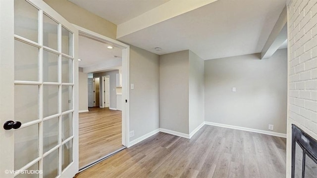 unfurnished room featuring wood finished floors, baseboards, recessed lighting, and a large fireplace