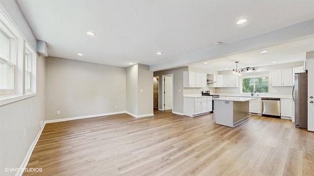 kitchen featuring appliances with stainless steel finishes, baseboards, light wood-type flooring, a kitchen island, and white cabinets